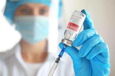 Doctor filling syringe with vaccine against Covid-19, closeup. Space for text