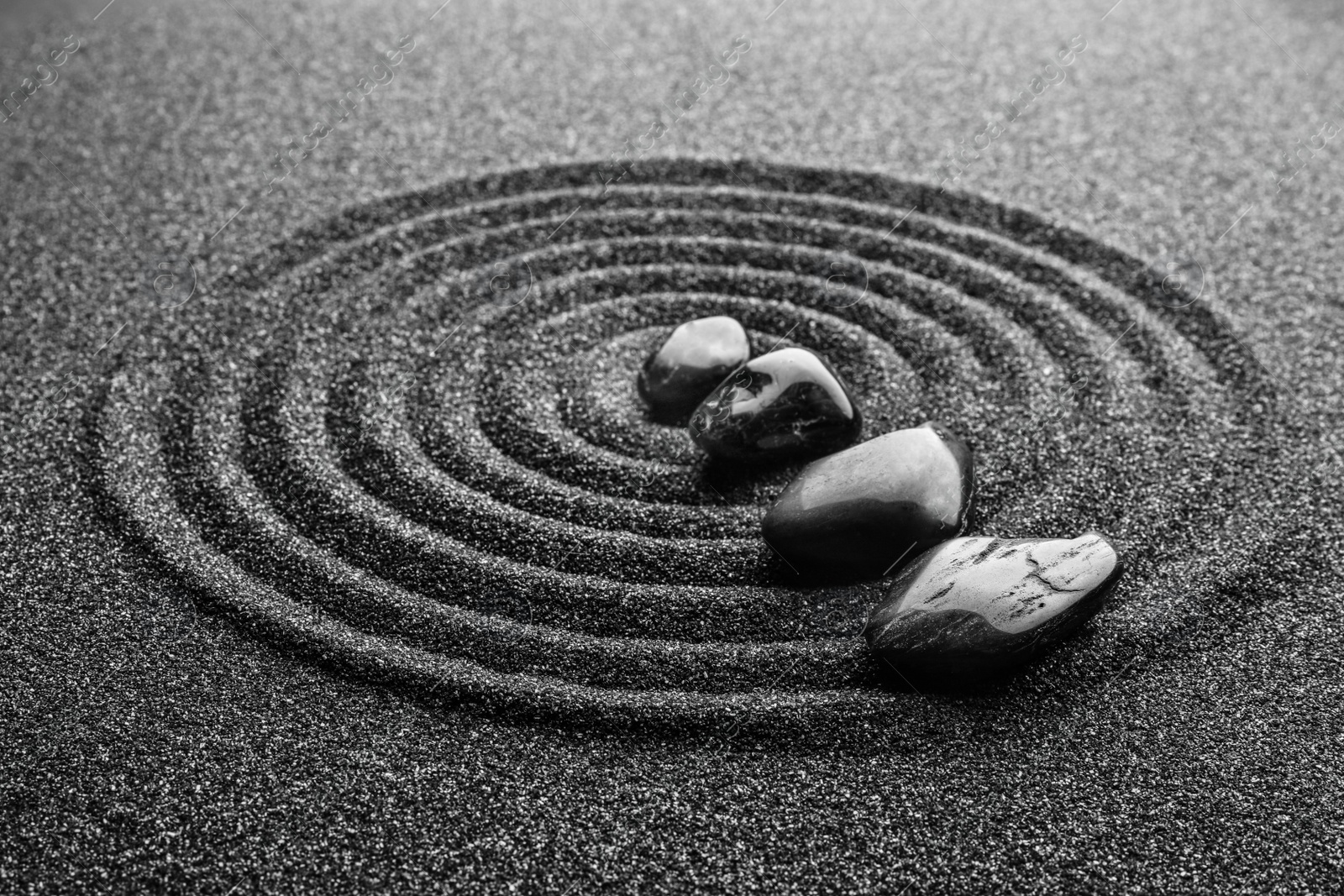 Photo of Black sand with stones and beautiful pattern. Zen concept