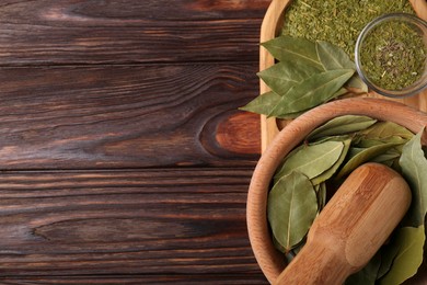 Photo of Whole and ground bay leaves on wooden table, top view. Space for text