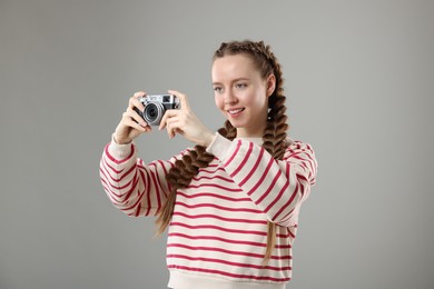Woman with braided hair taking photo on grey background