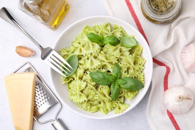 Photo of Delicious pasta with pesto sauce and basil on white table, flat lay
