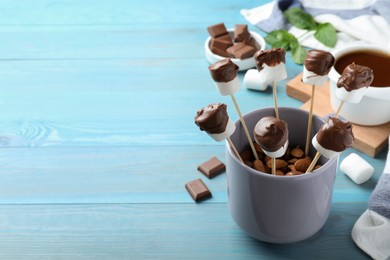 Photo of Delicious marshmallows covered with chocolate on blue wooden table. Space for text