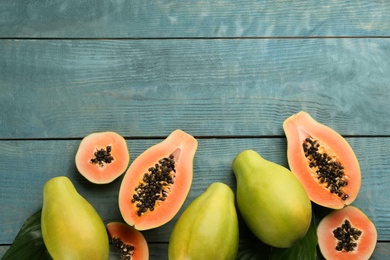 Photo of Fresh ripe papaya fruits on wooden table, flat lay. Space for text