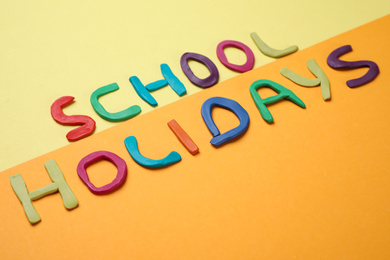 Photo of Phrase School Holidays made of modeling clay on color background