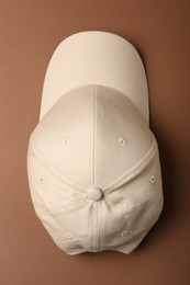 Photo of Baseball cap on brown background, top view. Mock up for design