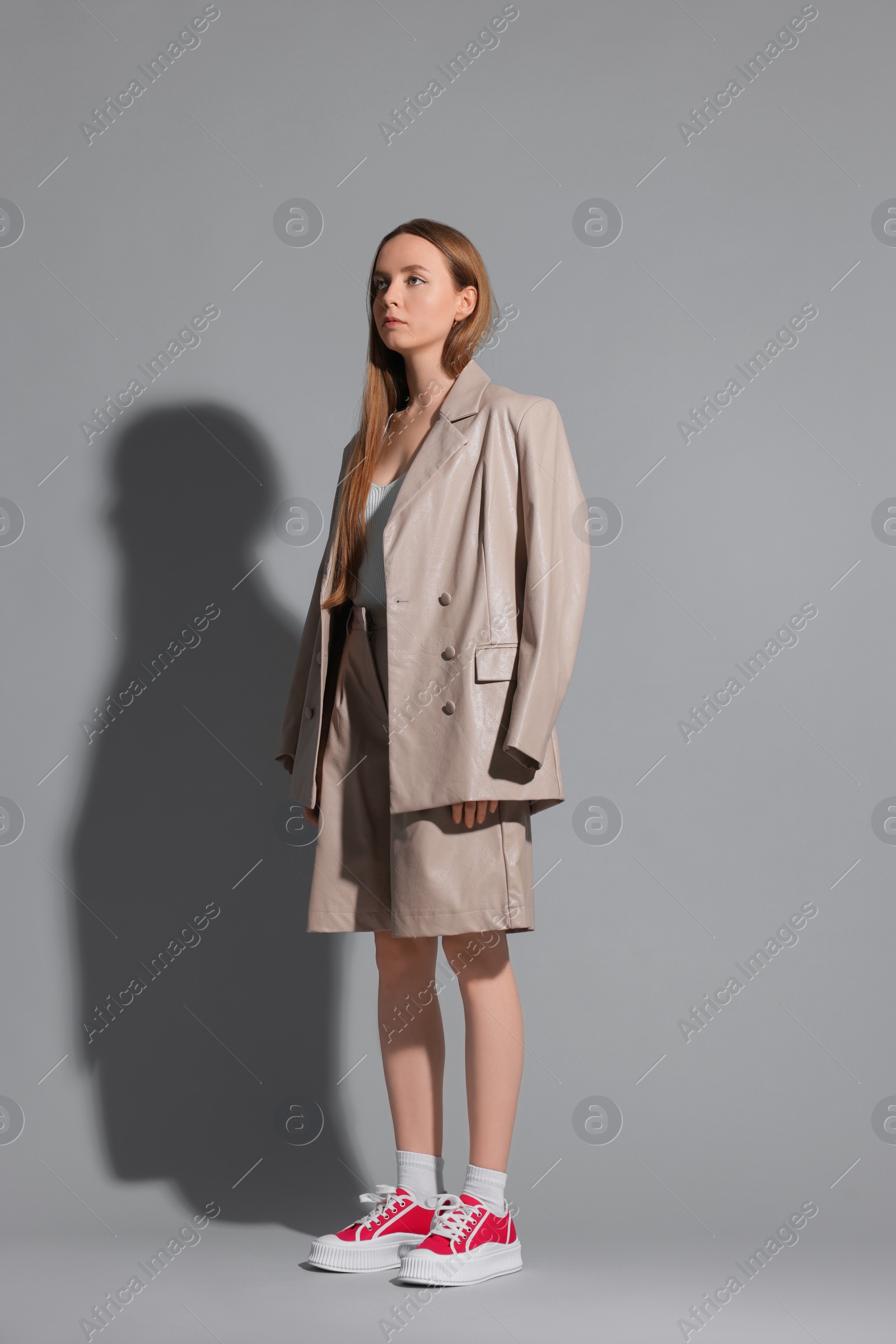 Photo of Stylish woman wearing red classic old school sneakers on light gray background