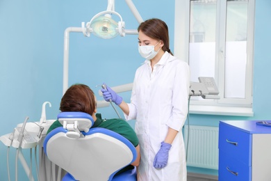 Photo of Professional dentist working with patient in modern clinic