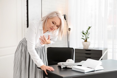 Photo of Mature woman having heart attack at workplace