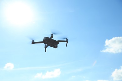 Modern drone with camera flying in sky on sunny day