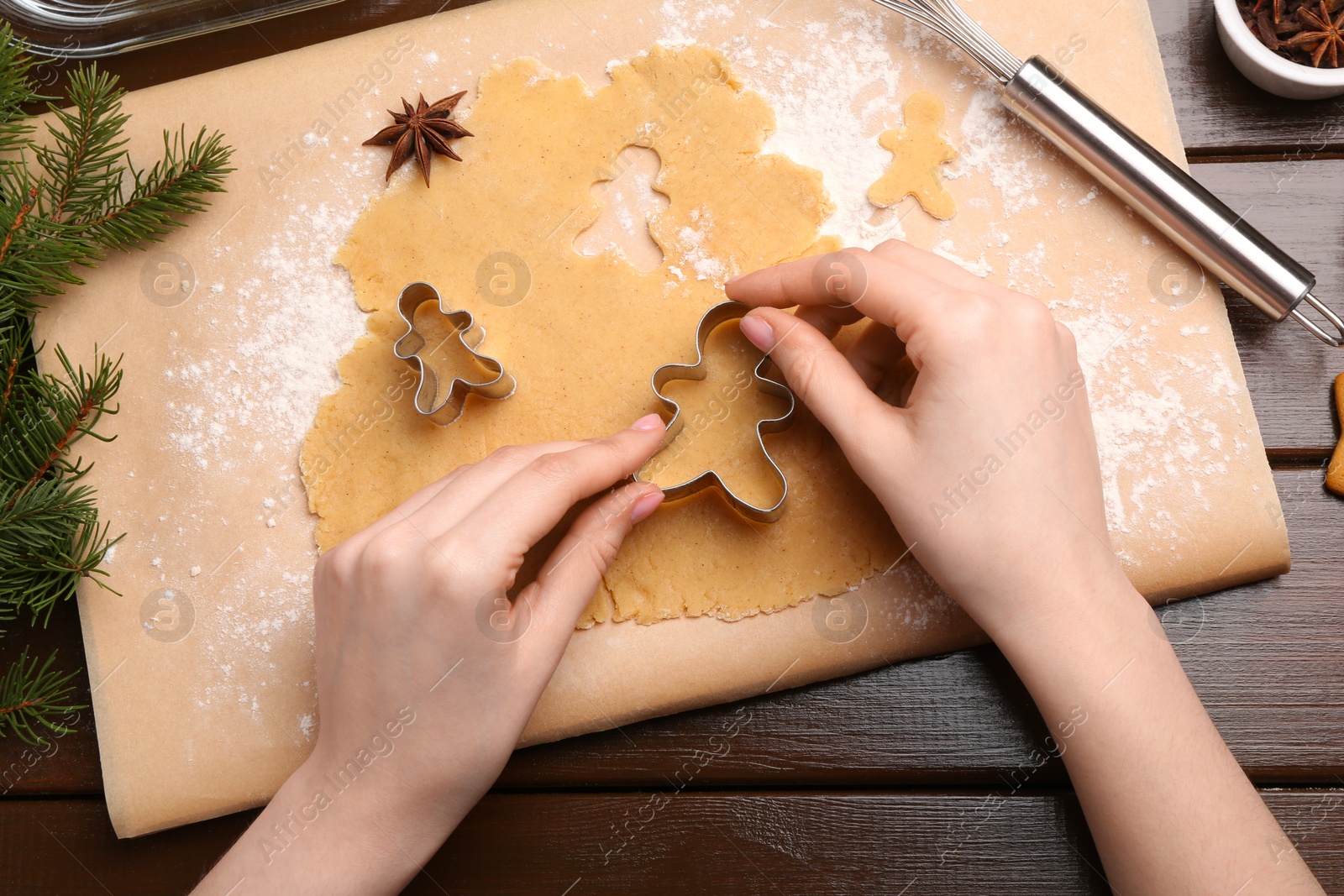 Photo of Woman making Christmas cookies with cutters at wooden table, top view