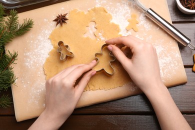 Photo of Woman making Christmas cookies with cutters at wooden table, top view