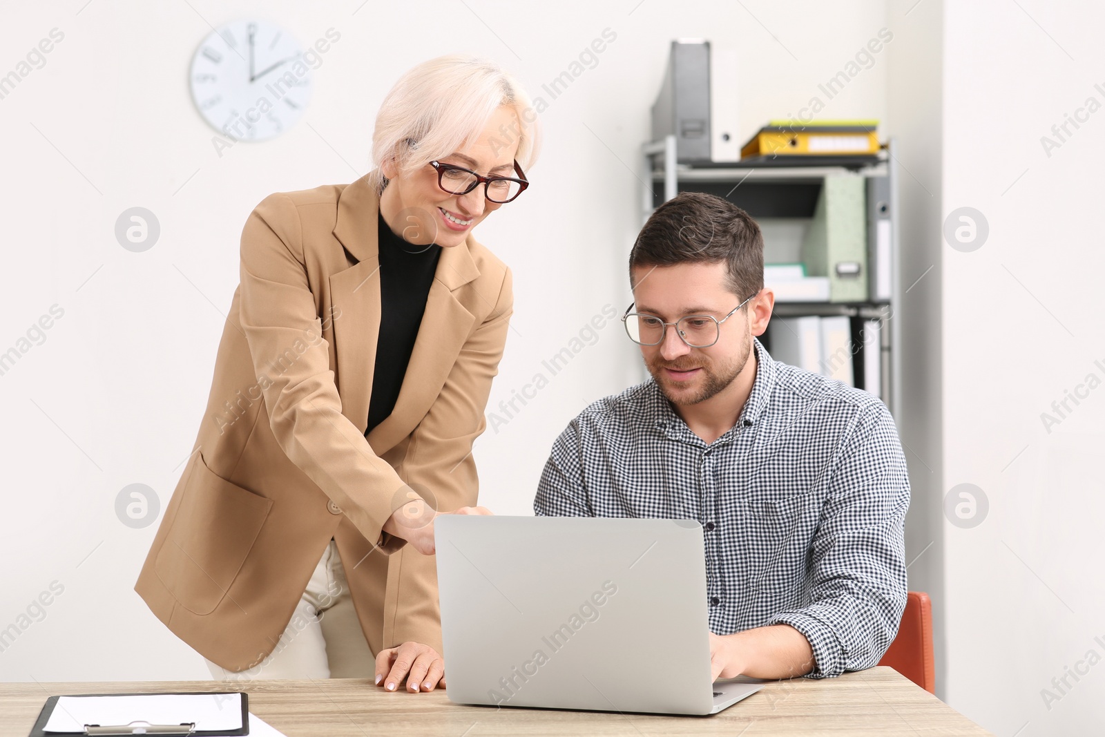 Photo of Boss and employee with laptop discussing work issues in office