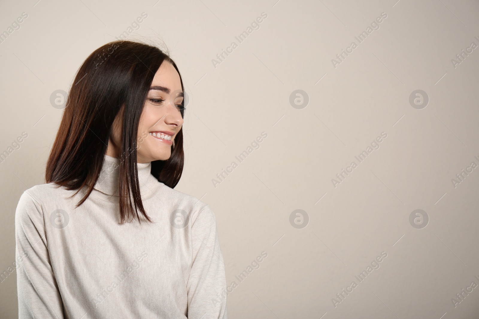 Photo of Portrait of pretty young woman with gorgeous chestnut hair and charming smile on light background, space for text