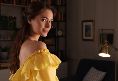 Beautiful young woman wearing yellow dress in room