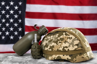 Photo of Military canteen, helmet and grenade on table against American flag background