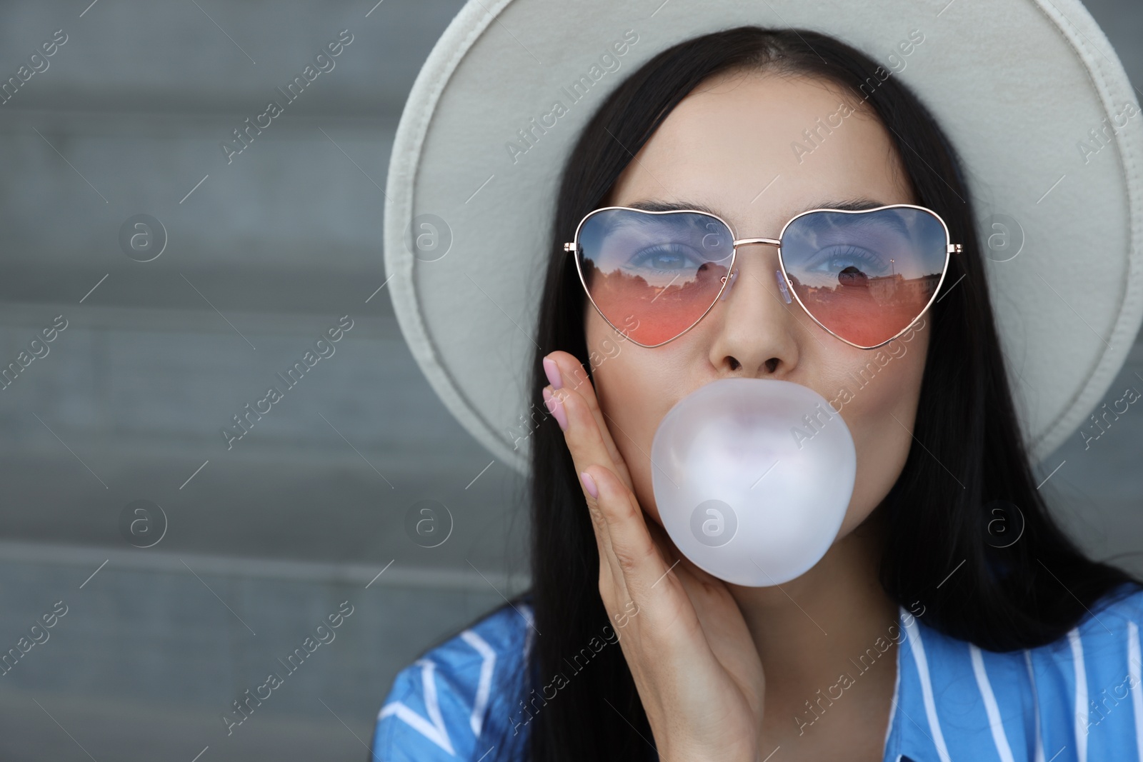 Photo of Stylish woman blowing gum near stairs outdoors