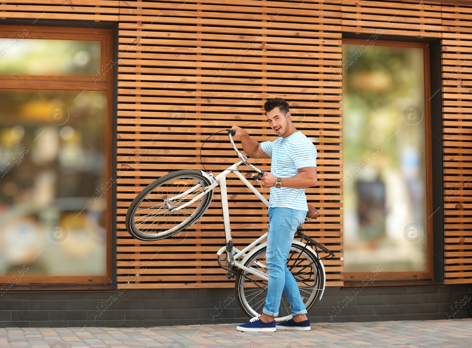 Photo of Handsome young hipster man with bicycle near wooden wall outdoors