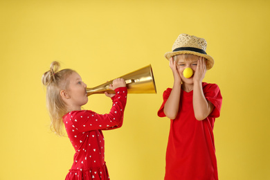 Funny kids with megaphone on yellow background. April fool's day