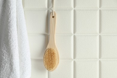 Photo of Bath accessories. Bamboo brush and terry towel on white tiled wall, space for text