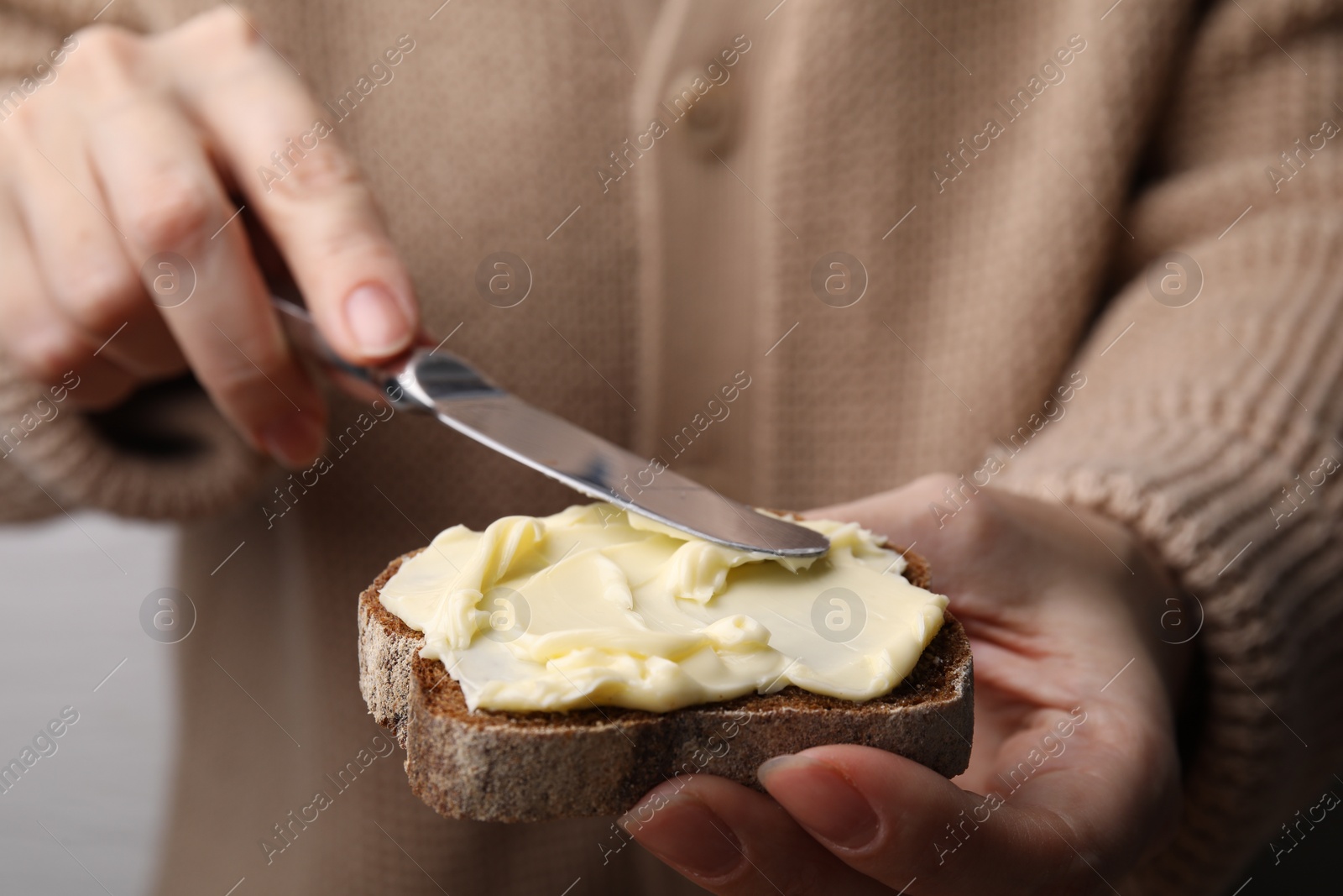 Photo of Woman spreading butter onto bread, closeup view
