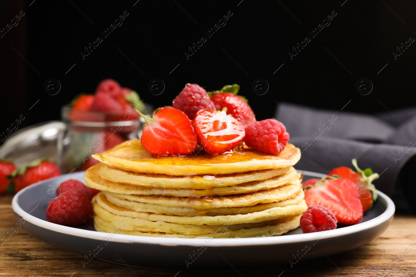 Photo of Tasty pancakes with fresh berries and honey on wooden table, closeup