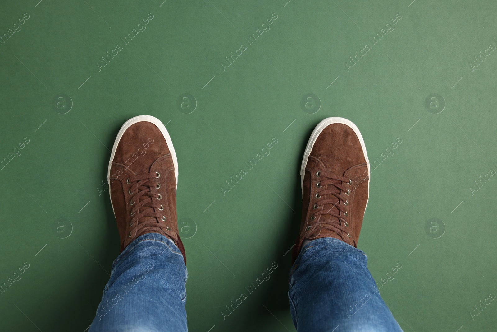 Photo of Man in stylish sneakers standing on green background, top view