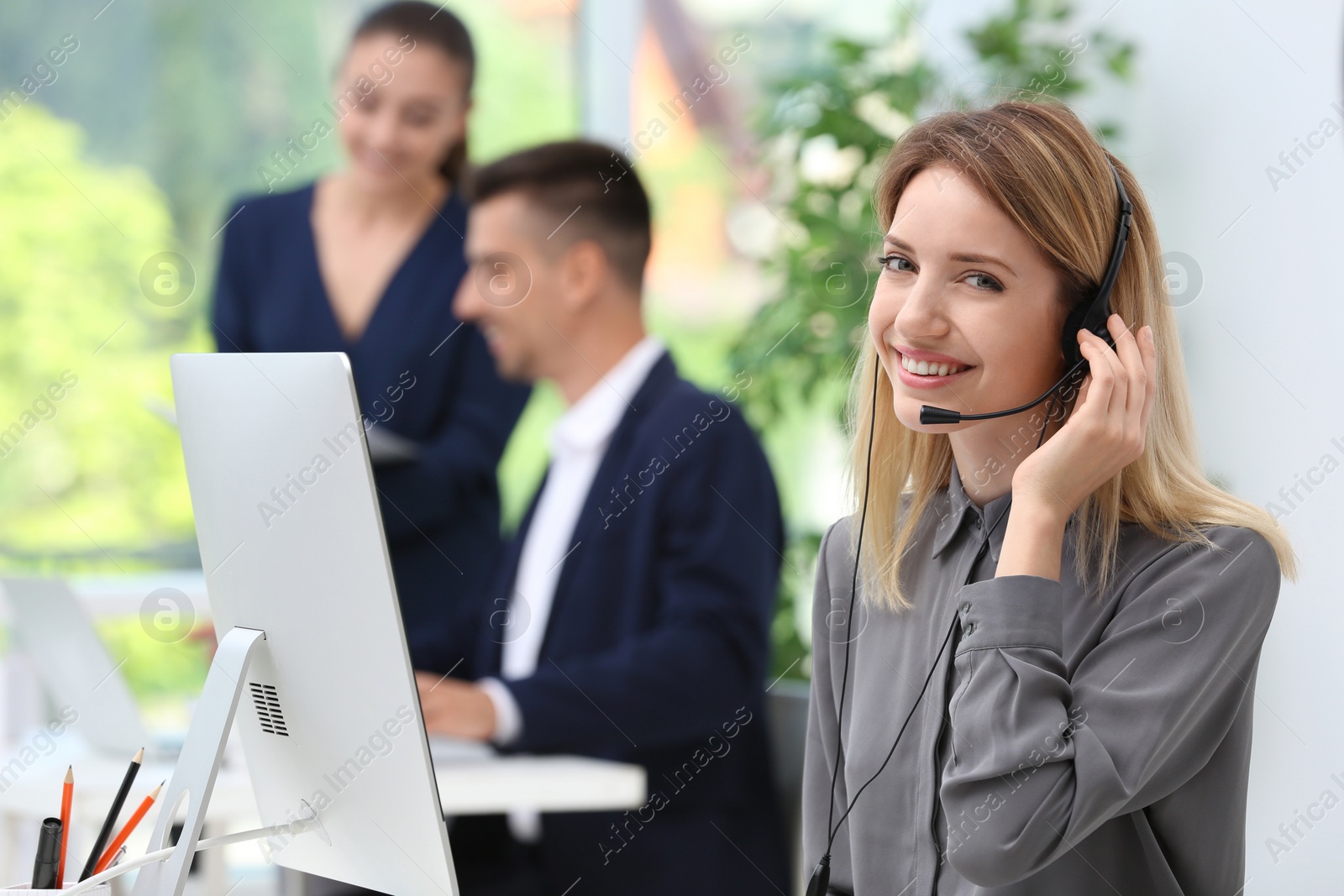 Photo of Female receptionist with headset at desk in office