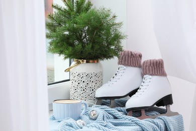 Photo of Pair of ice skates and Christmas decor near window indoors