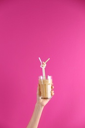 Young woman holding glass of healthy smoothie on color background