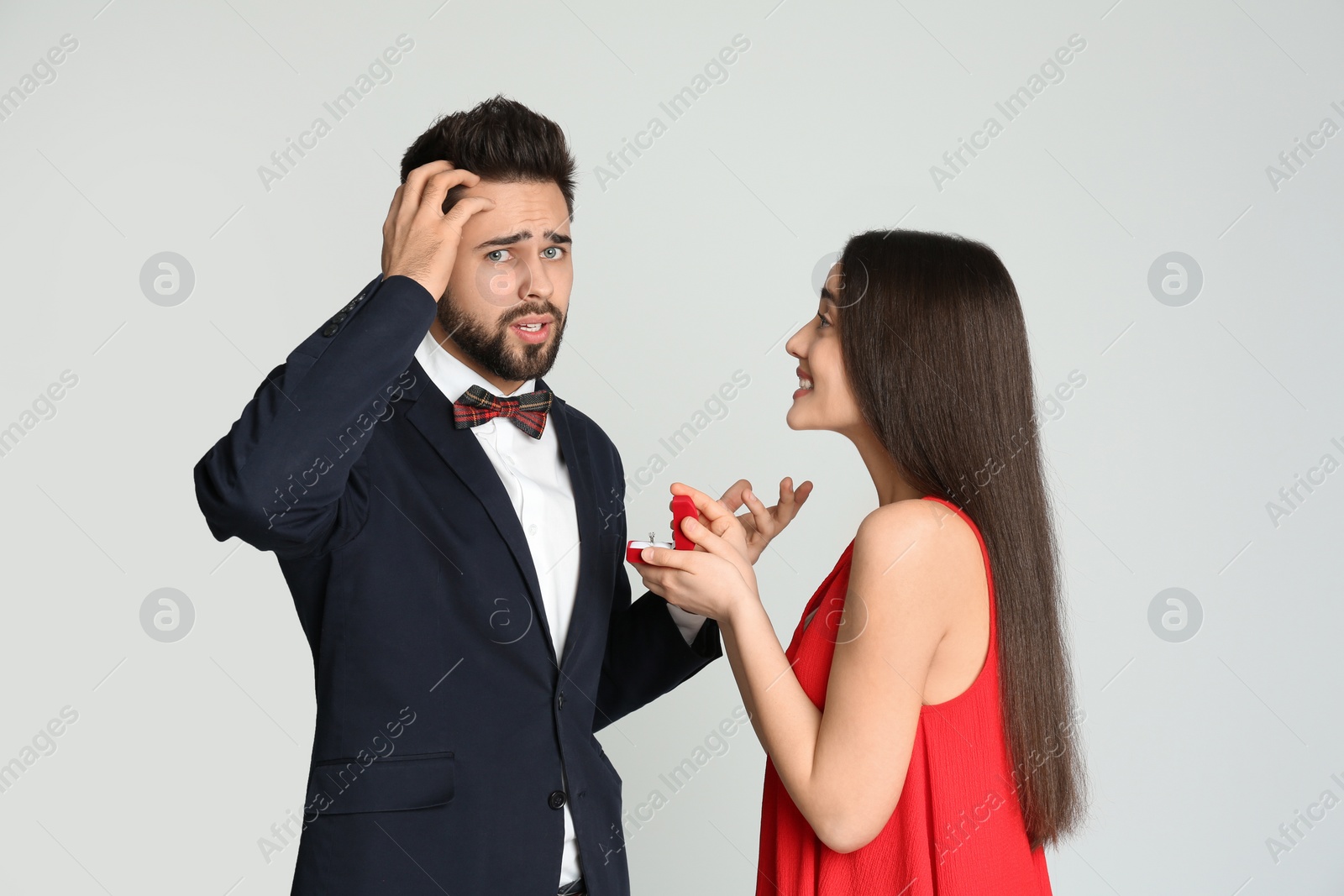 Photo of Young woman with engagement ring making marriage proposal to her boyfriend on light grey background