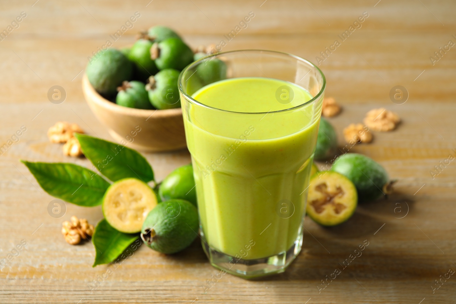 Photo of Fresh feijoa smoothie and fresh fruits on wooden table, closeup