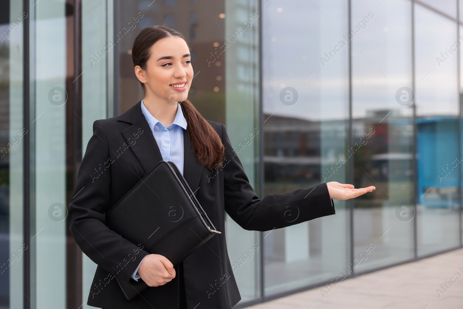 Photo of Female real estate agent with leather portfolio outdoors