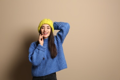 Young woman wearing warm clothes on color background, space for text. Winter season