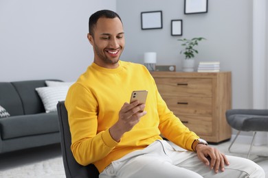 Photo of Happy man sending message via smartphone indoors