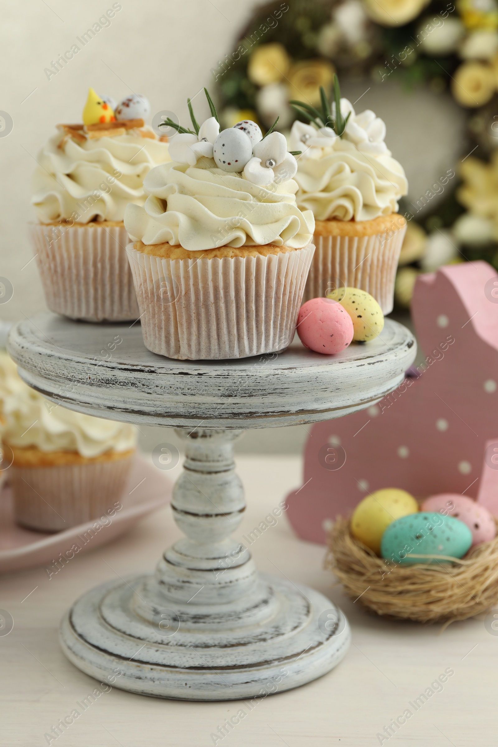 Photo of Tasty Easter cupcakes with vanilla cream and festive decor on light wooden table