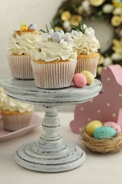 Tasty Easter cupcakes with vanilla cream and festive decor on light wooden table