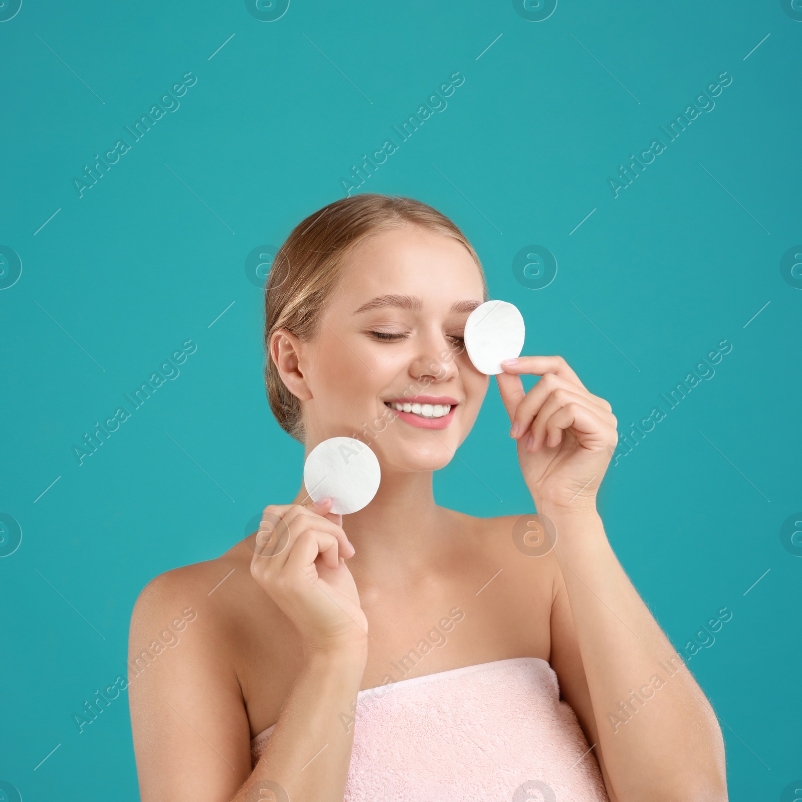 Photo of Beautiful young woman with cotton pads on turquoise background