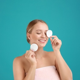 Photo of Beautiful young woman with cotton pads on turquoise background