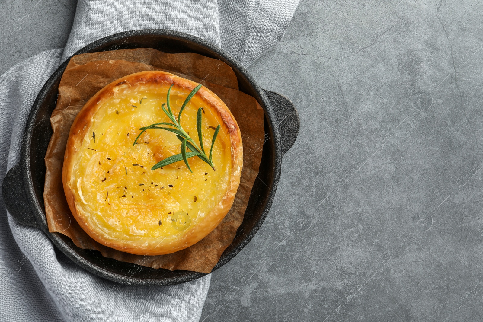 Photo of Dish with tasty baked brie cheese on grey table, top view. Space for text