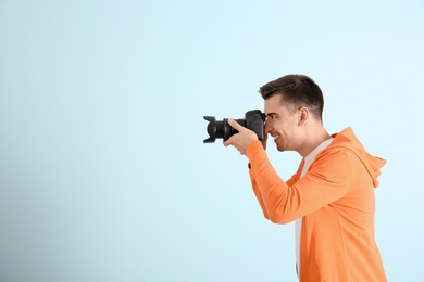 Male photographer with camera on light background
