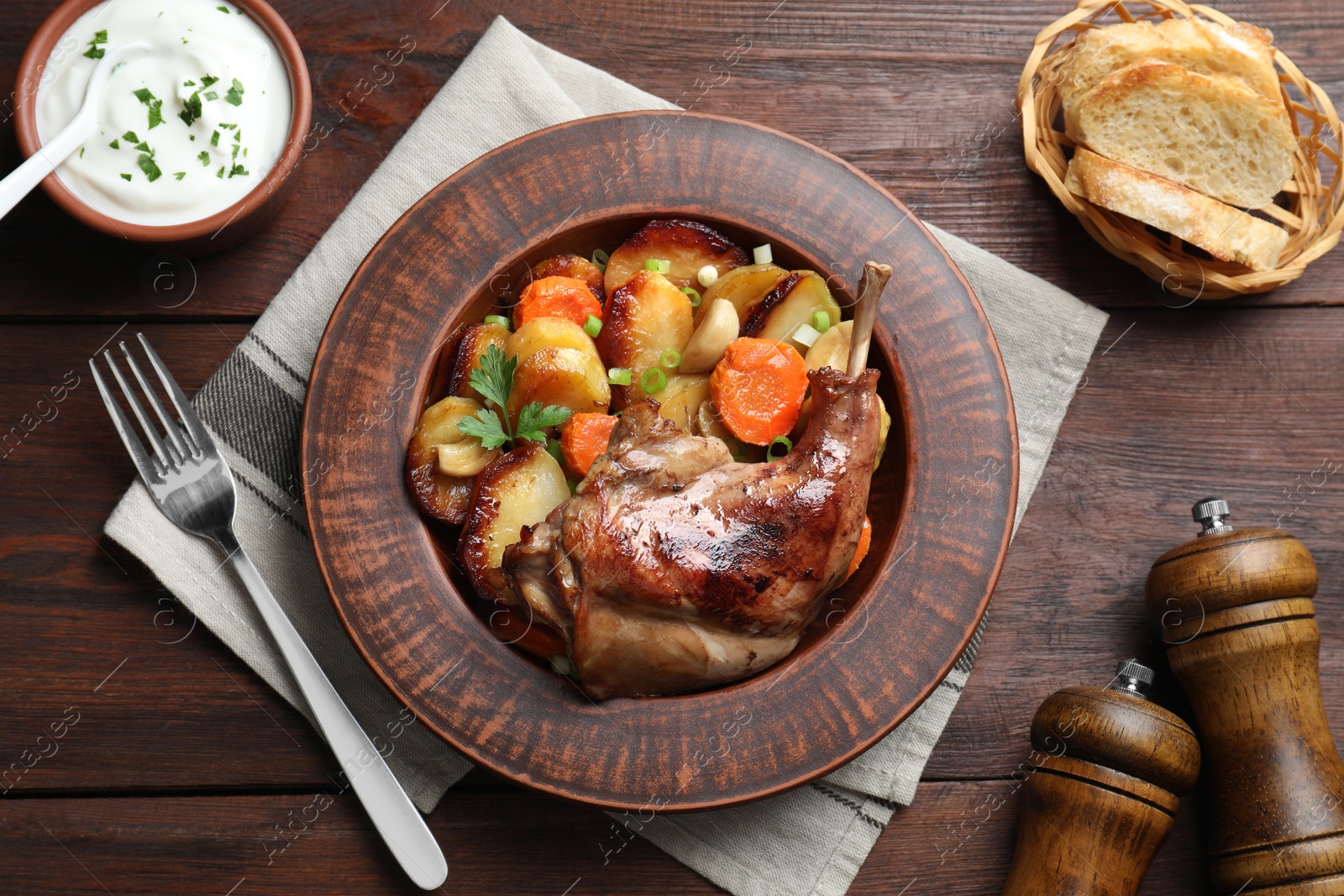 Photo of Tasty cooked rabbit meat with vegetables served on wooden table, flat lay