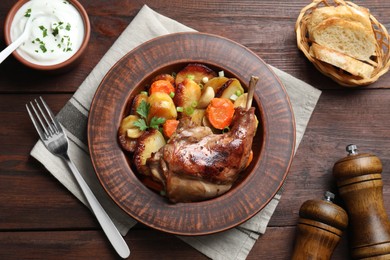 Tasty cooked rabbit meat with vegetables served on wooden table, flat lay