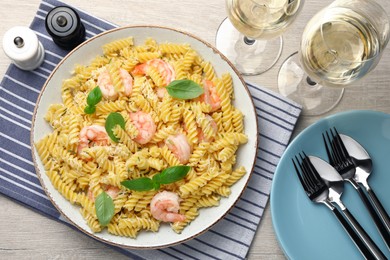 Photo of Delicious pasta with shrimps, basil and parmesan cheese served on light wooden table, flat lay