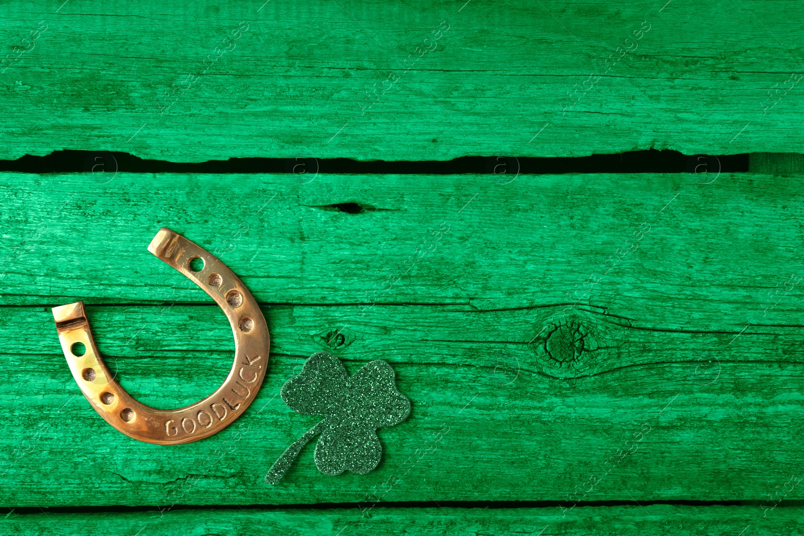 Image of St. Patrick's day. Decorative clover leaf and golden horseshoe on green wooden background, flat lay. Space for text