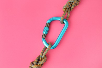 Photo of One metal carabiner with ropes on bright pink background, top view