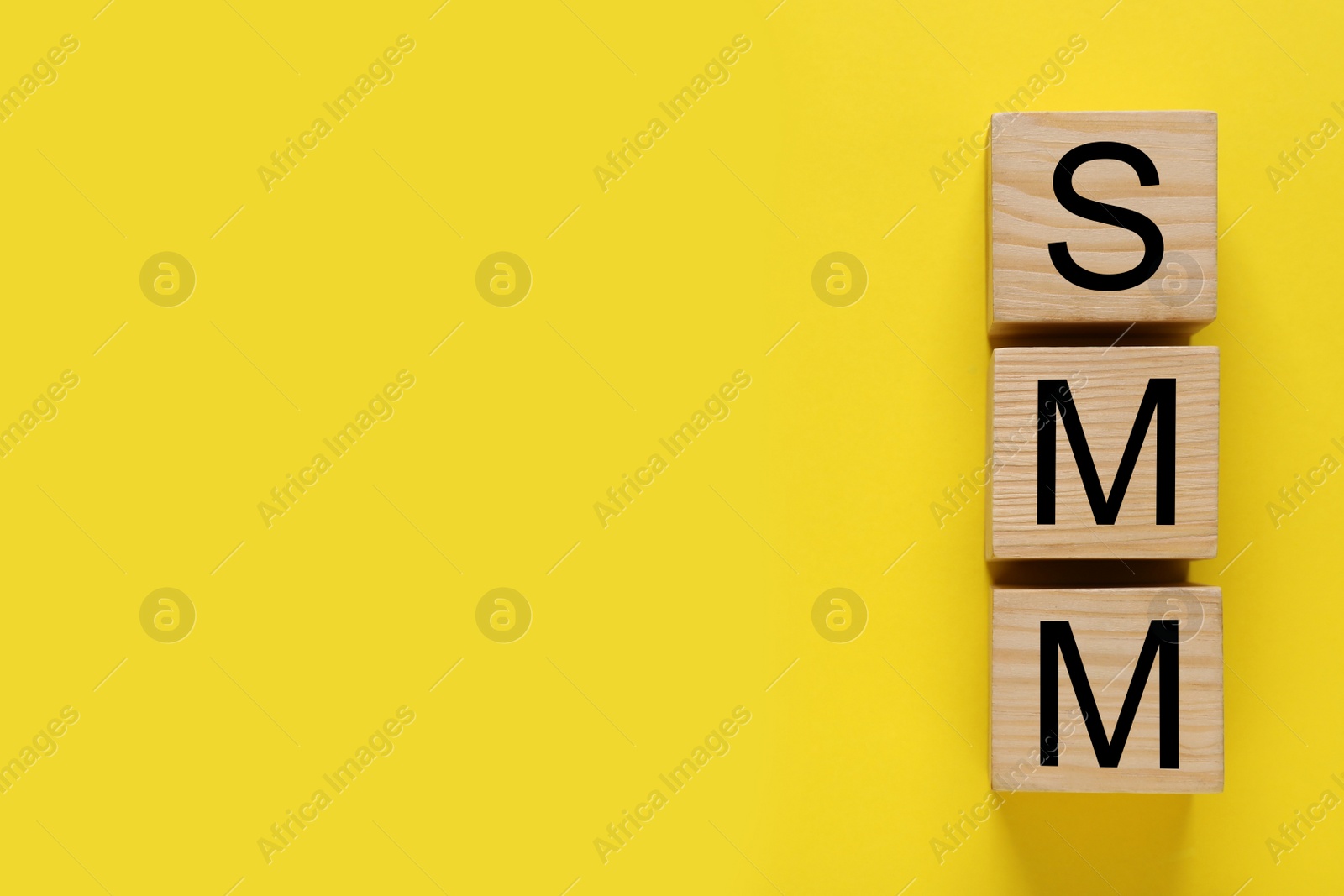 Photo of Cubes with abbreviation SMM (Social media marketing) on yellow background, flat lay. Space for text