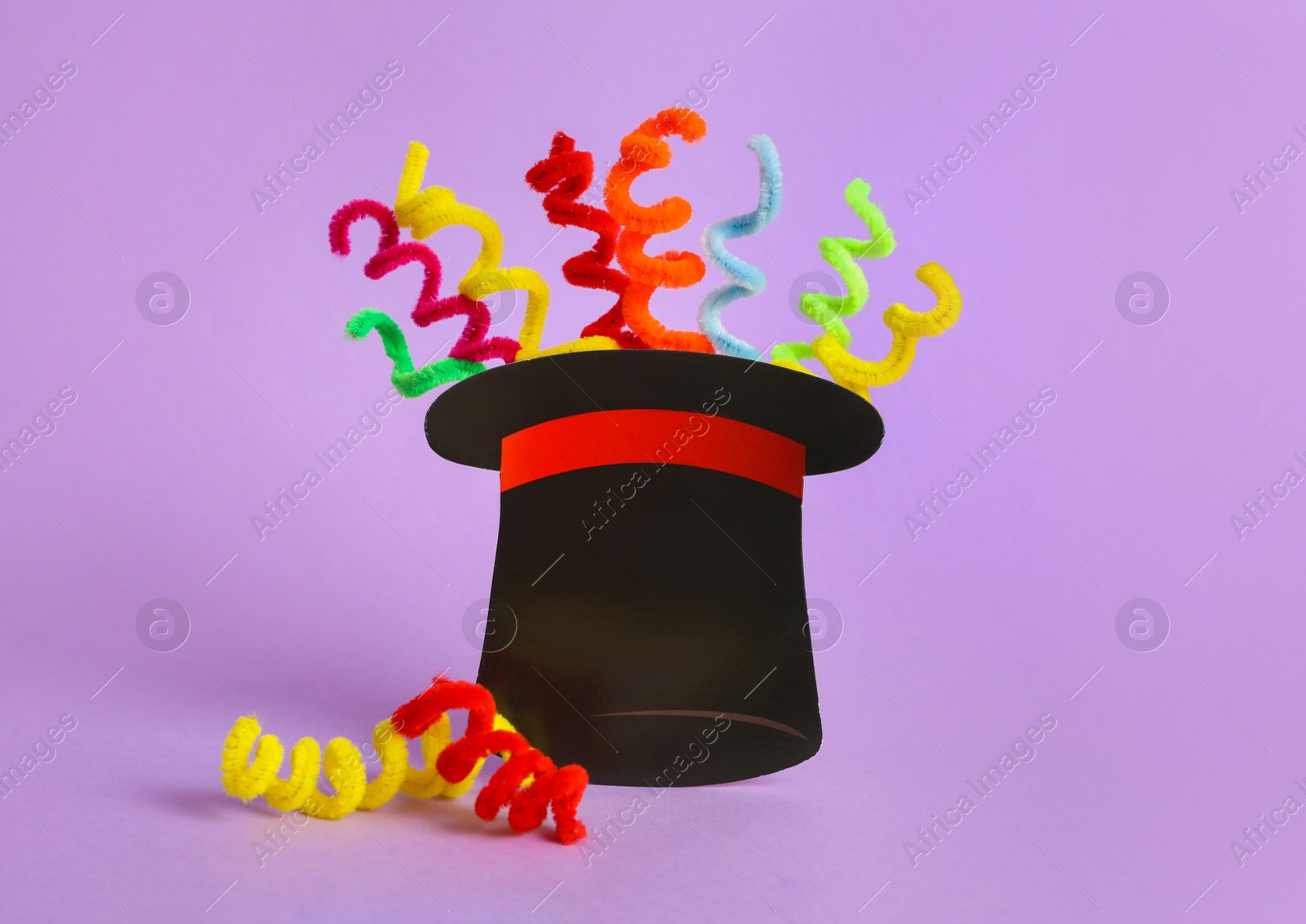 Photo of Paper hat and colorful fluffy wires on violet background