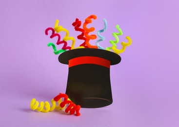 Photo of Paper hat and colorful fluffy wires on violet background