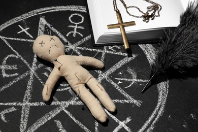 Photo of Ceremonial items and voodoo doll in ritual circle drawn on black table