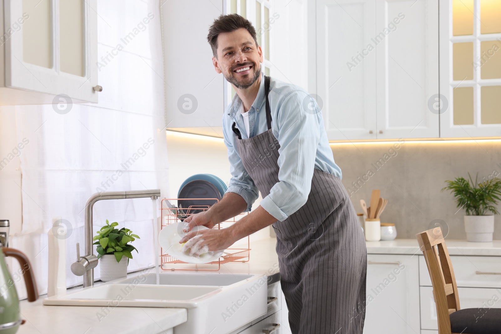 Photo of Man washing plate above sink in kitchen